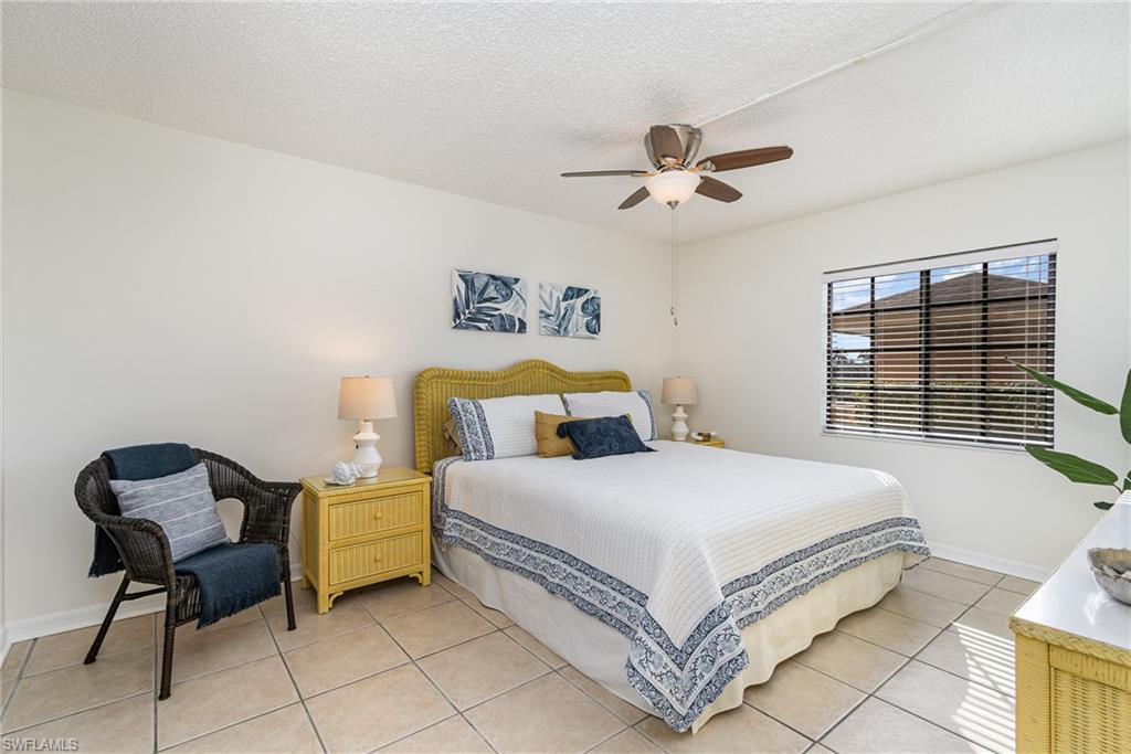 5535 Rattlesnake Hammock Road, Unit 103 Naples, FL 34113 - Photo 9 of 25 Primary Bedroom with ceiling fan and coastal decor.