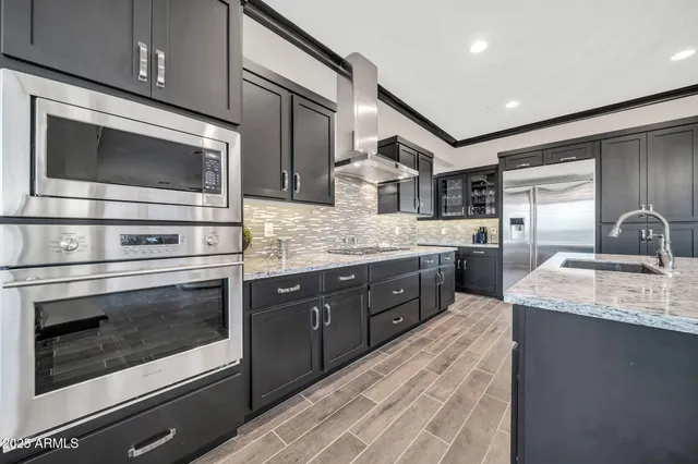 a kitchen with stainless steel appliances kitchen island granite countertop a table chairs in it and wooden floors