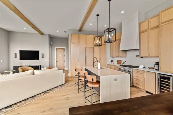 a kitchen with stainless steel appliances a sink a stove a refrigerator cabinets and living room view