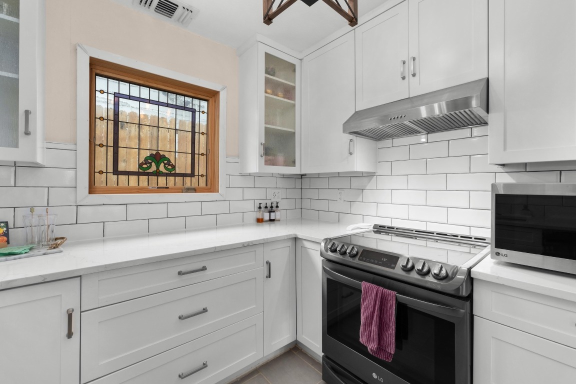4610 Avenue B, Unit B Austin, TX 78751 - Photo 3 of 22 Kitchen featuring stainless steel appliances, white cabinets, under cabinet range hood, glass insert cabinets, and light stone countertops
