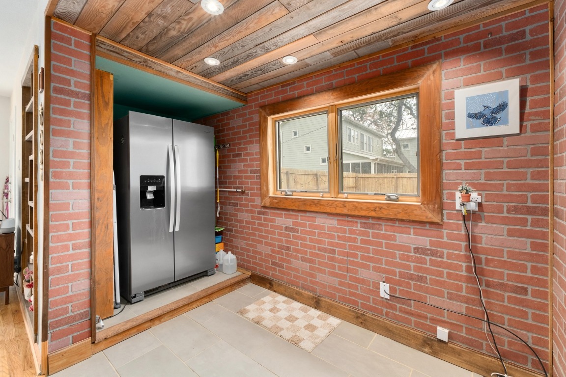 4610 Avenue B, Unit B Austin, TX 78751 - Photo 9 of 22 Kitchen featuring brick wall, stainless steel fridge with ice dispenser, tile patterned flooring, wood ceiling, and recessed lighting