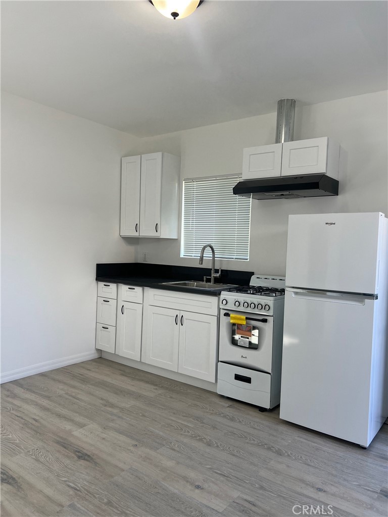 18740 Valerio Street Reseda, CA 91335 - Photo 2 of 5 a kitchen with cabinets and wooden floor