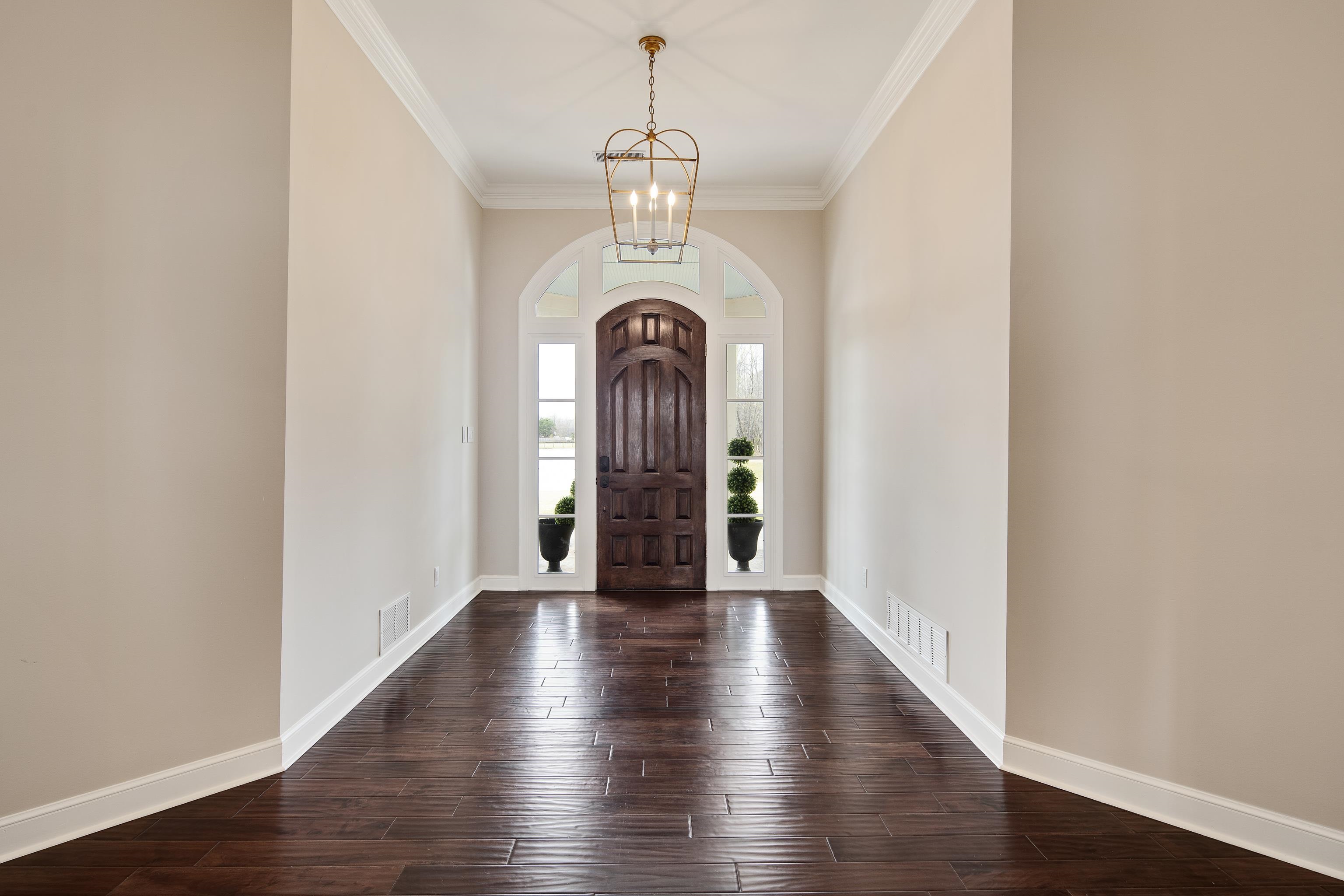 10471 Collierville Road Collierville, TN 38017 - Photo 2 of 40 Entrance foyer with visible vents, arched walkways, crown molding, a chandelier, and dark wood-style flooring