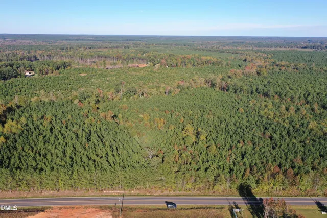 an aerial view of residential houses with outdoor space and trees