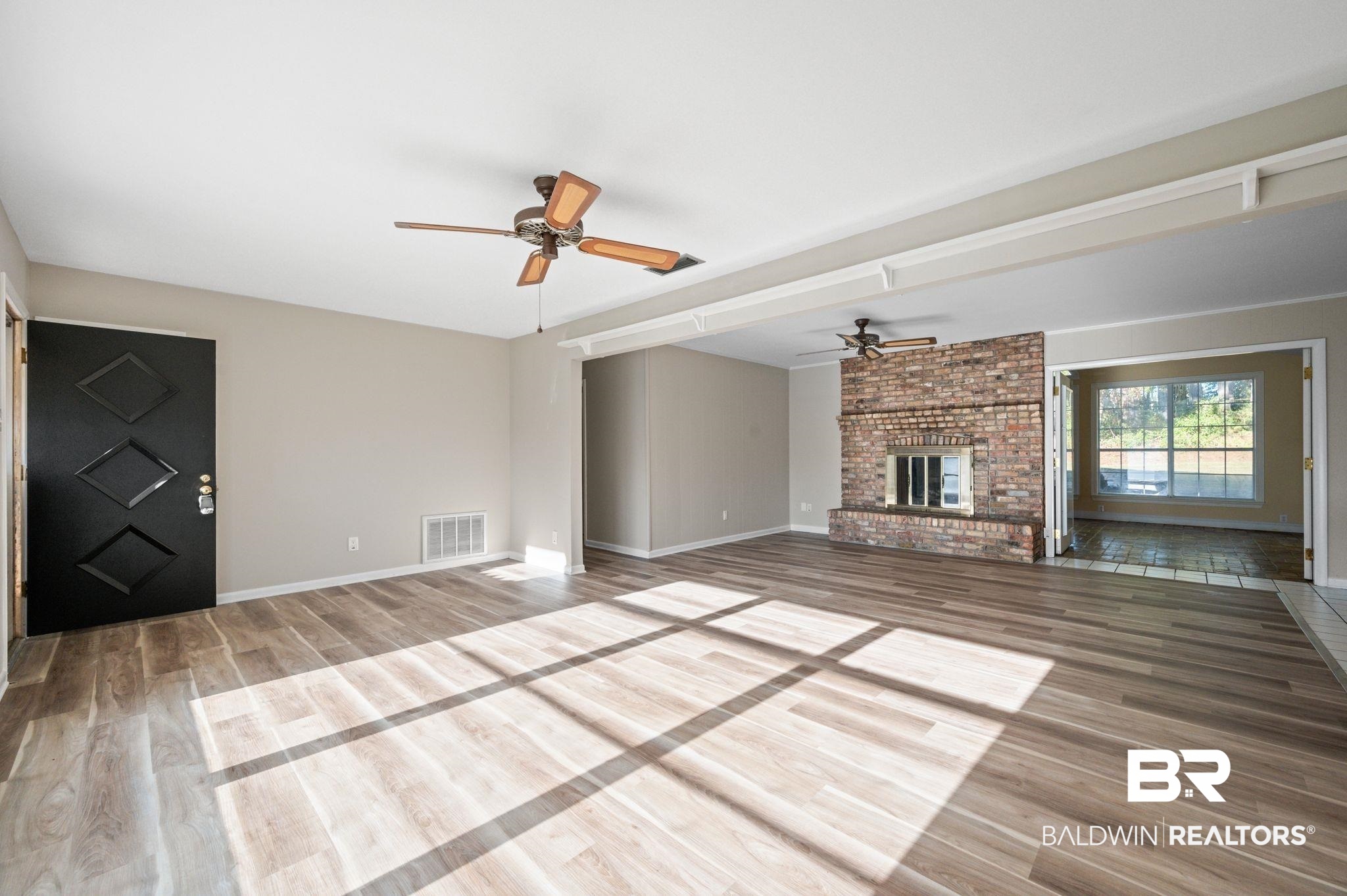 909 Caroline Avenue Daphne, AL 36526 - Photo 7 of 46 Unfurnished living room featuring wood-type flooring, a brick fireplace, and ceiling fan