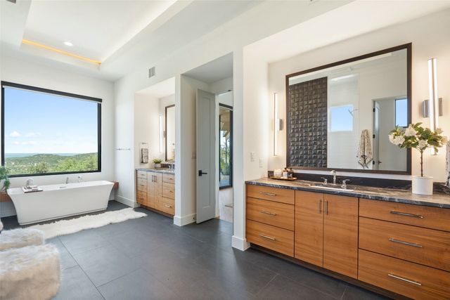 a spacious bathroom with a tub a double vanity sink a mirror and a shower
