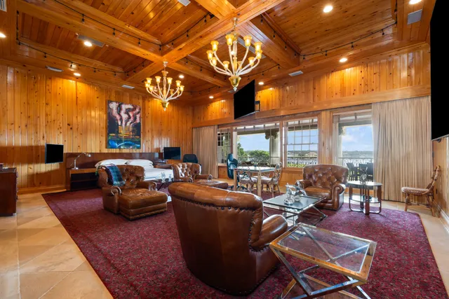 a living room with furniture a chandelier and a floor to ceiling window