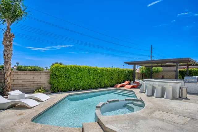 a backyard of a house with table and chairs under an umbrella