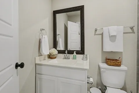 a bathroom with a toilet sink vanity and mirror