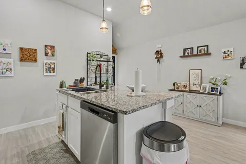 a kitchen with granite countertop a sink a stove and cabinets