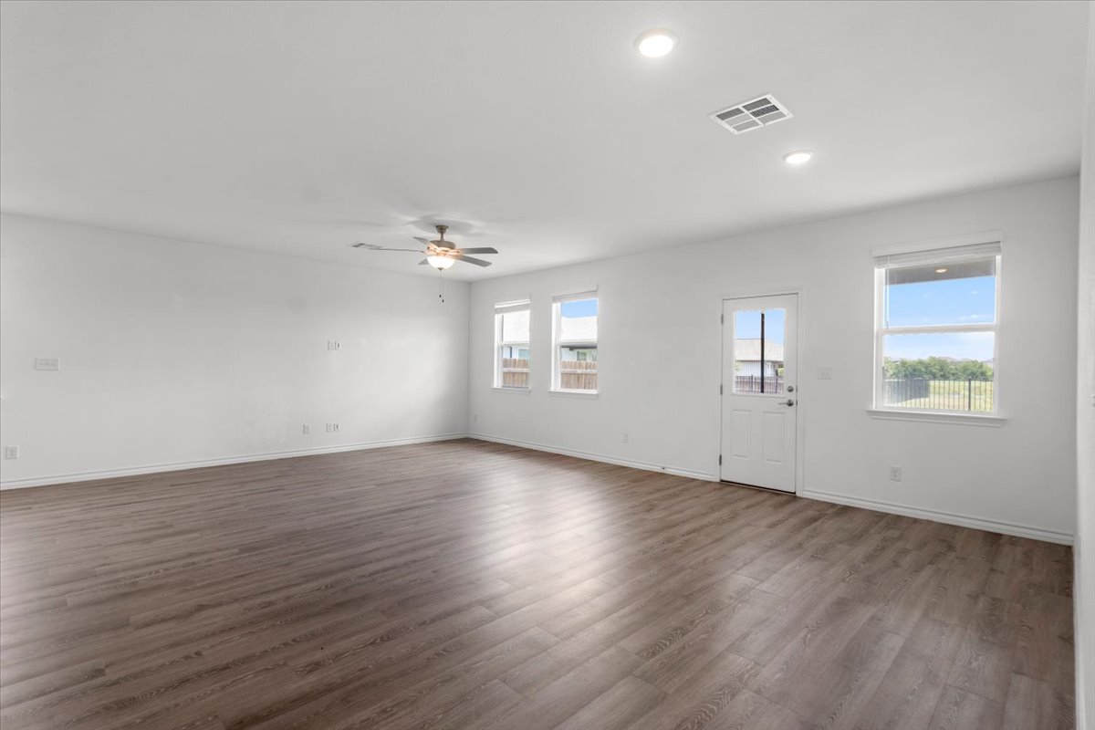 500 Stinchcomb Road Hutto, TX 78634 - Photo 10 of 37 A spacious living area featuring contemporary wood-look flooring and multiple windows for abundant natural illumination.