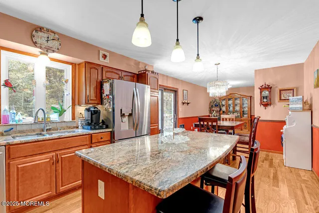 a kitchen with stainless steel appliances kitchen island granite countertop a table chairs in it and wooden floors