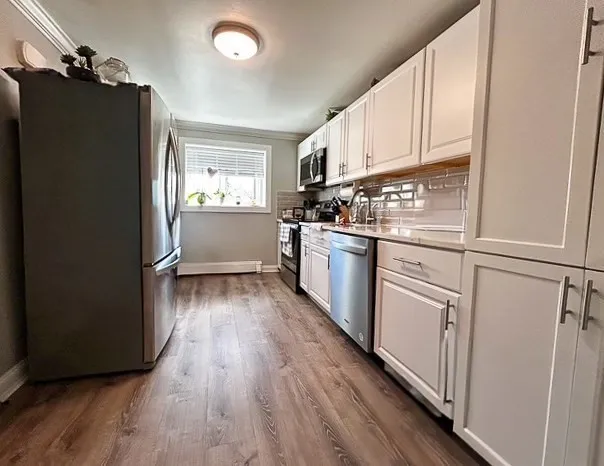 a kitchen with white cabinets and wooden floor