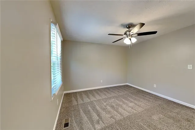an empty room with a window and a fan