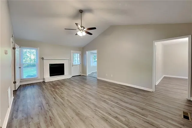 a view of empty room with wooden floor fan and window