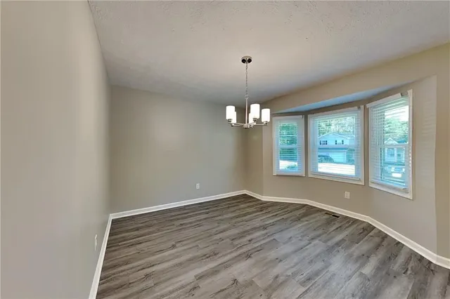 a view of an empty room with window and chandelier fan