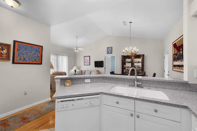 a view with granite countertop a sink dishwasher and white cabinets with wooden floor