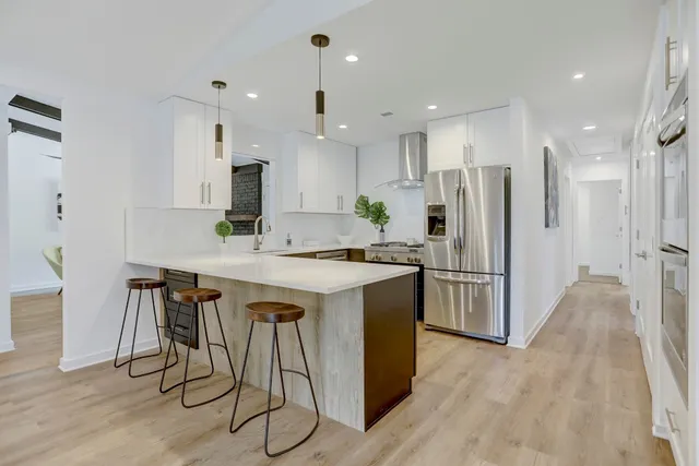 a kitchen with stainless steel appliances granite countertop a refrigerator a sink dishwasher a stove and a refrigerator with wooden floor