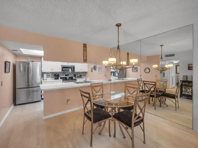 a kitchen with refrigerator a dining table and chairs