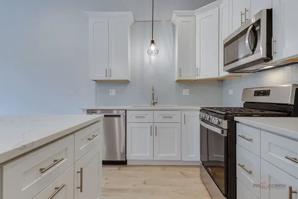 a kitchen with stainless steel appliances granite countertop white cabinets granite counter tops and a wooden floors