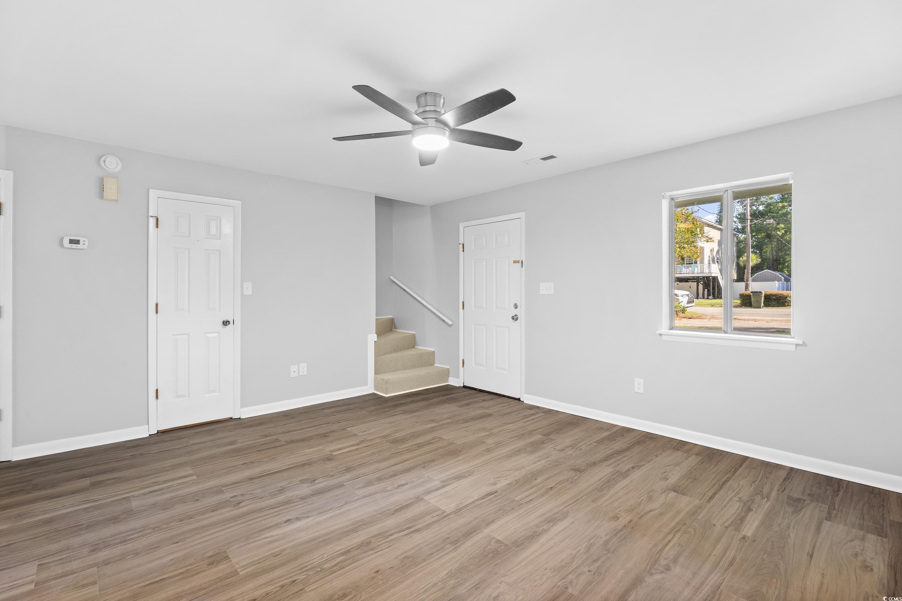 617 Surfside Drive Surfside Beach, SC 29575 - Photo 12 of 39 Unfurnished living room featuring light wood finished floors, a ceiling fan, and stairs