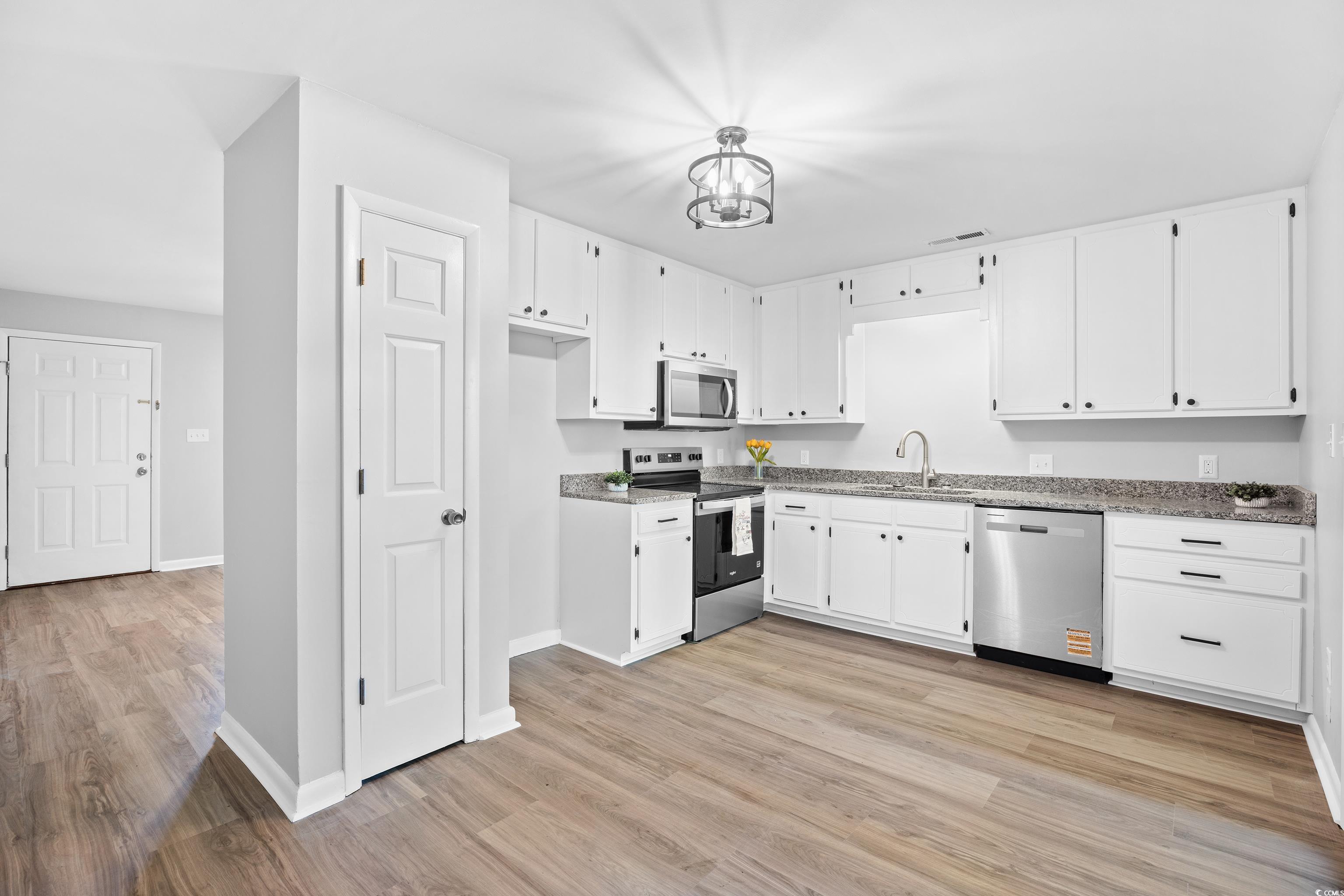 617 Surfside Drive Surfside Beach, SC 29575 - Photo 15 of 39 Kitchen featuring appliances with stainless steel finishes, white cabinetry, light wood-style floors, and a chandelier