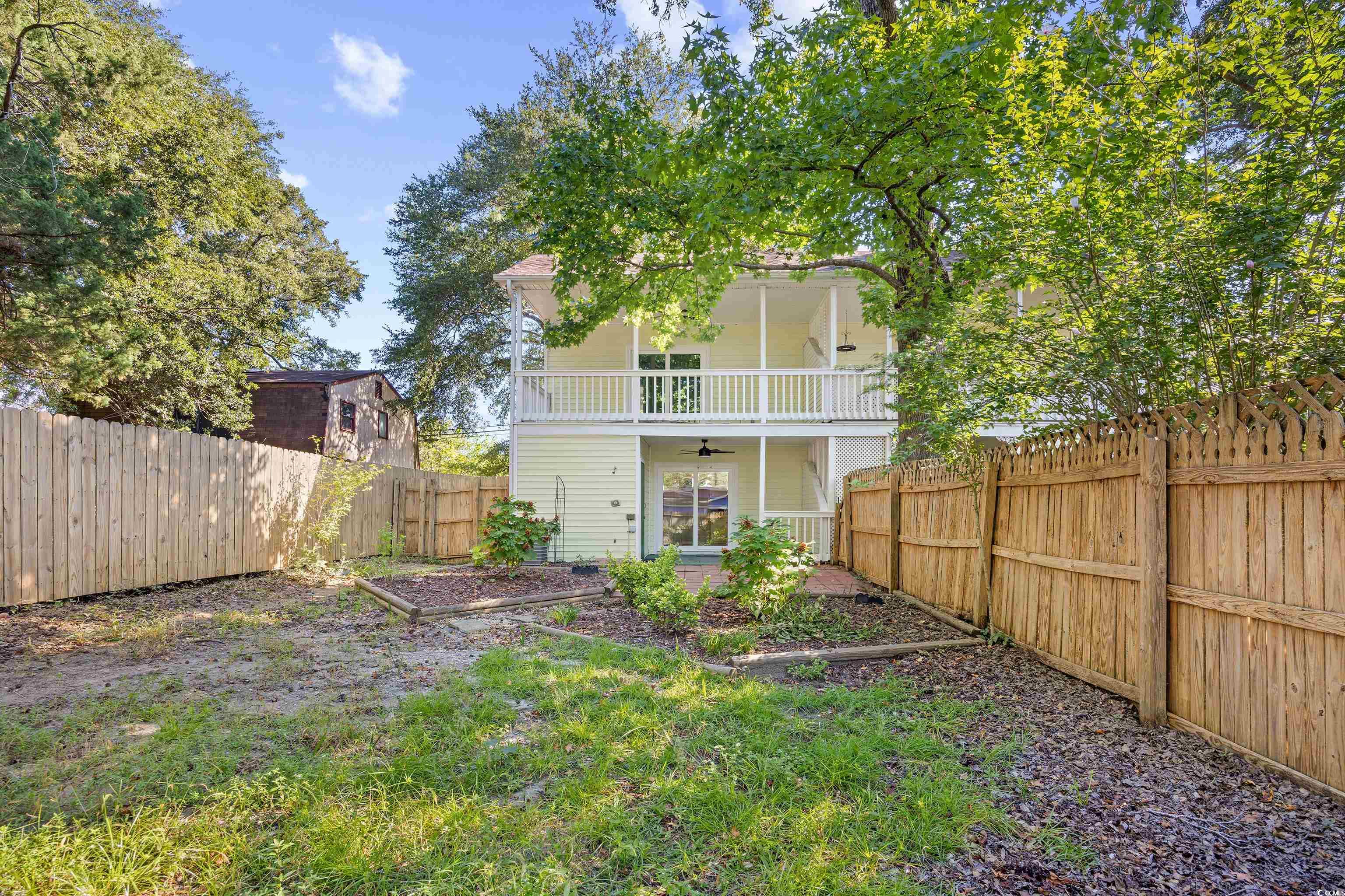 617 Surfside Drive Surfside Beach, SC 29575 - Photo 8 of 39 Back of house with ceiling fan, a fenced backyard, and a balcony