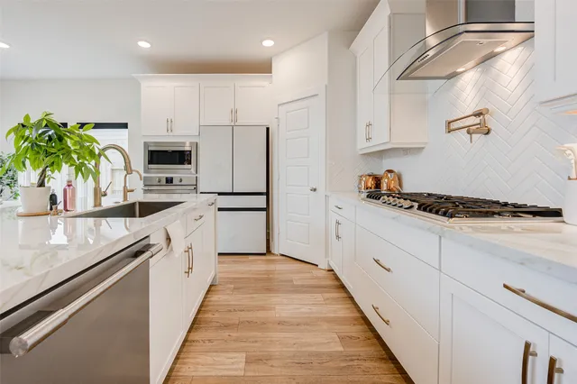 a white kitchen with stainless steel appliances granite countertop lots of counter top space and cabinets