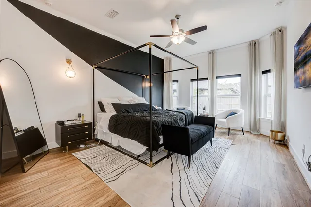a bedroom with a bed a chandelier and wooden floor