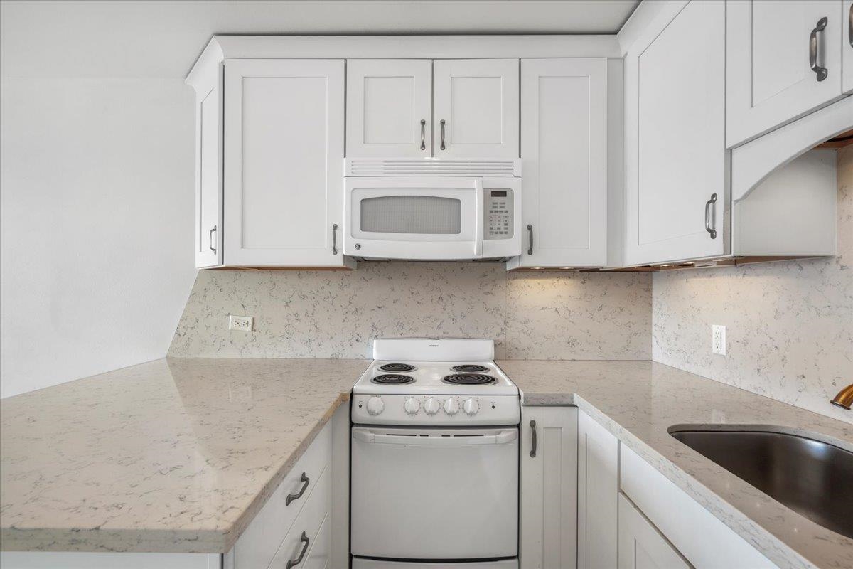 1403 Front Street, Unit 309 Lahaina, HI 96761 - Photo 10 of 33 a kitchen with granite countertop white cabinets and sink