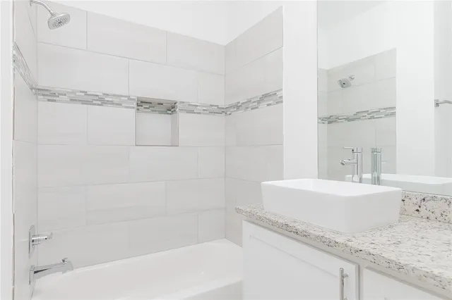 a bathroom with a granite countertop bathtub shower and sink