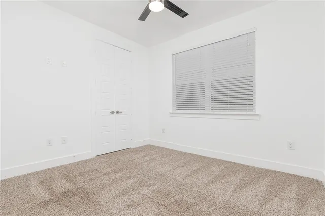 an empty room with a window and a ceiling fan