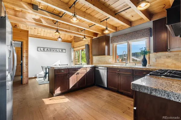 a dining hall with stainless steel appliances granite countertop a table chairs and a refrigerator