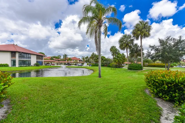 a view of a house with a big yard and palm trees