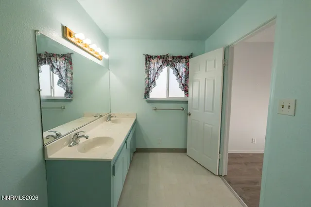 an empty room with wooden floor chandelier and windows