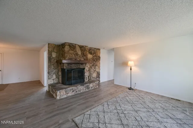 a view of empty room with wooden floor and fireplace