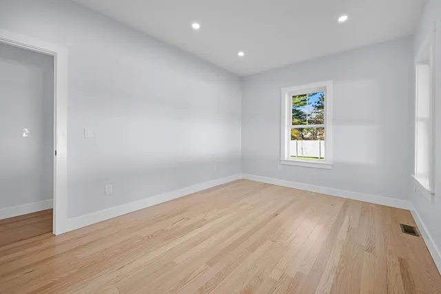an empty room with wooden floor and window