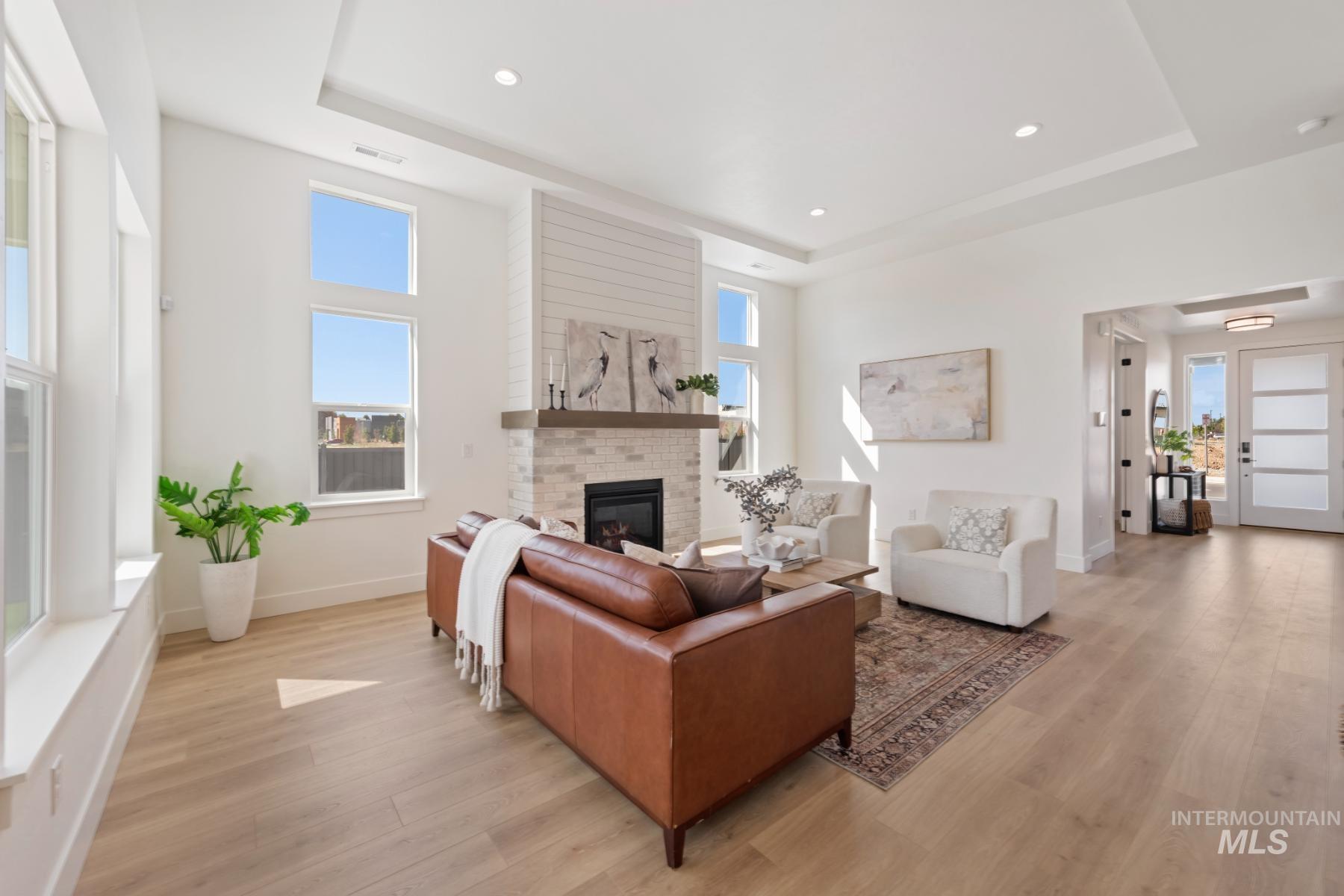 945 West Malbar Street Meridian, ID 83646 - Photo 11 of 42 Living room with a tray ceiling, a brick fireplace, light wood-type flooring, and recessed lighting
