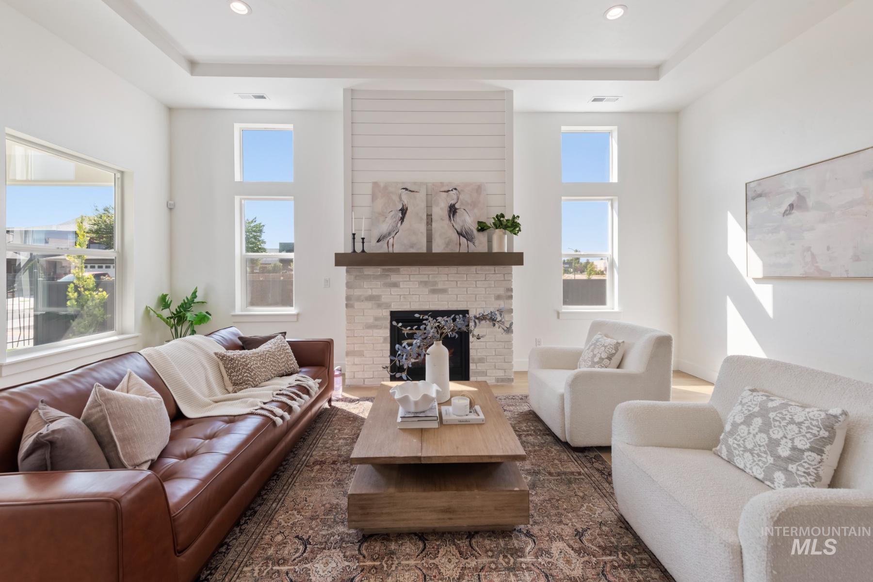 945 West Malbar Street Meridian, ID 83646 - Photo 12 of 42 Living room featuring a brick fireplace, wood finished floors, recessed lighting, and a tray ceiling
