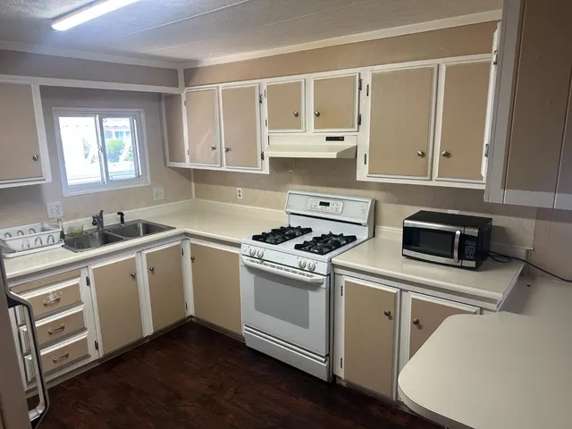 a kitchen with a stove white cabinetry and wooden floor