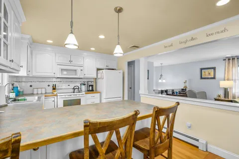 a kitchen with stainless steel appliances kitchen island granite countertop a dining table chairs and white cabinets