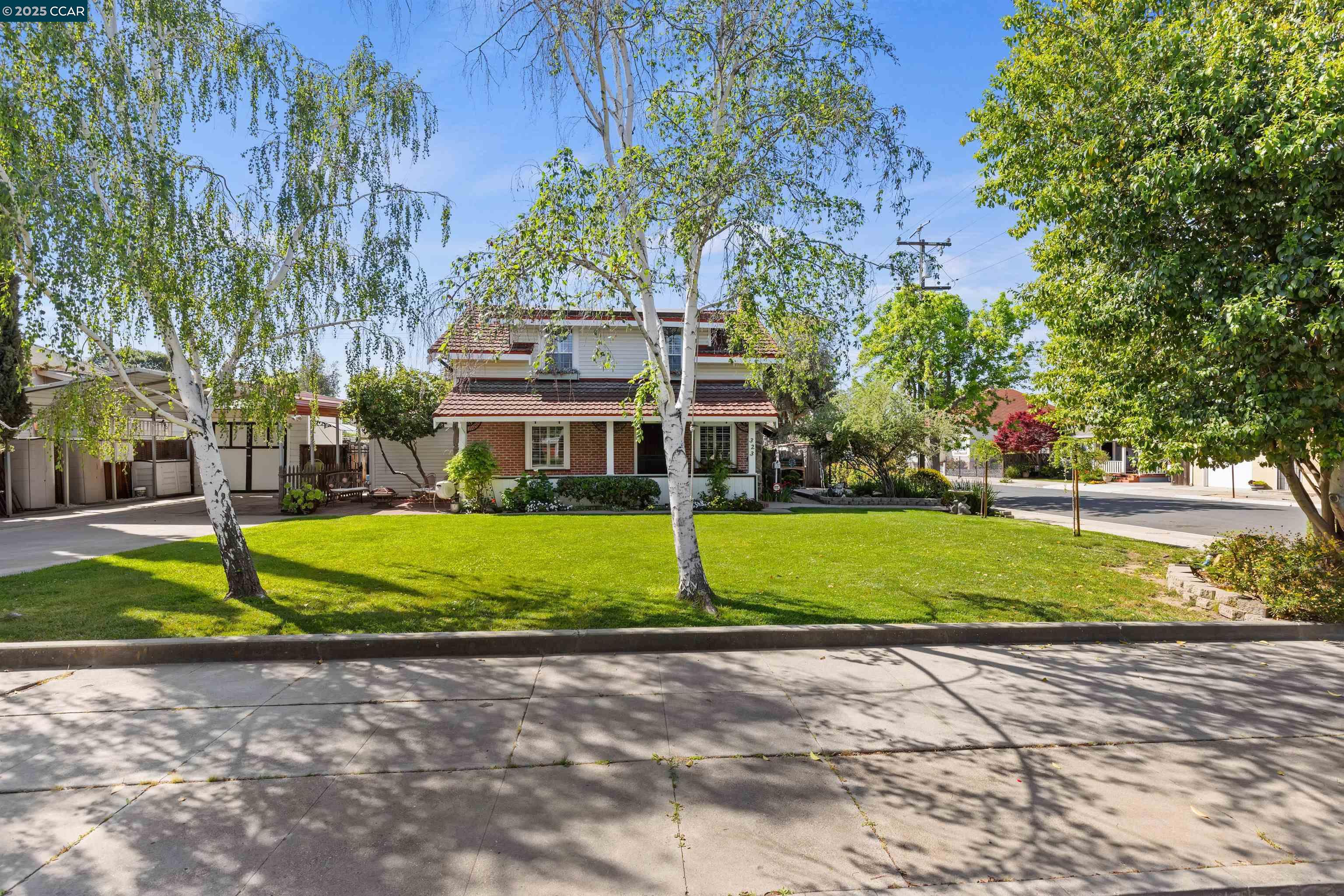 a view of a house with a yard and large trees