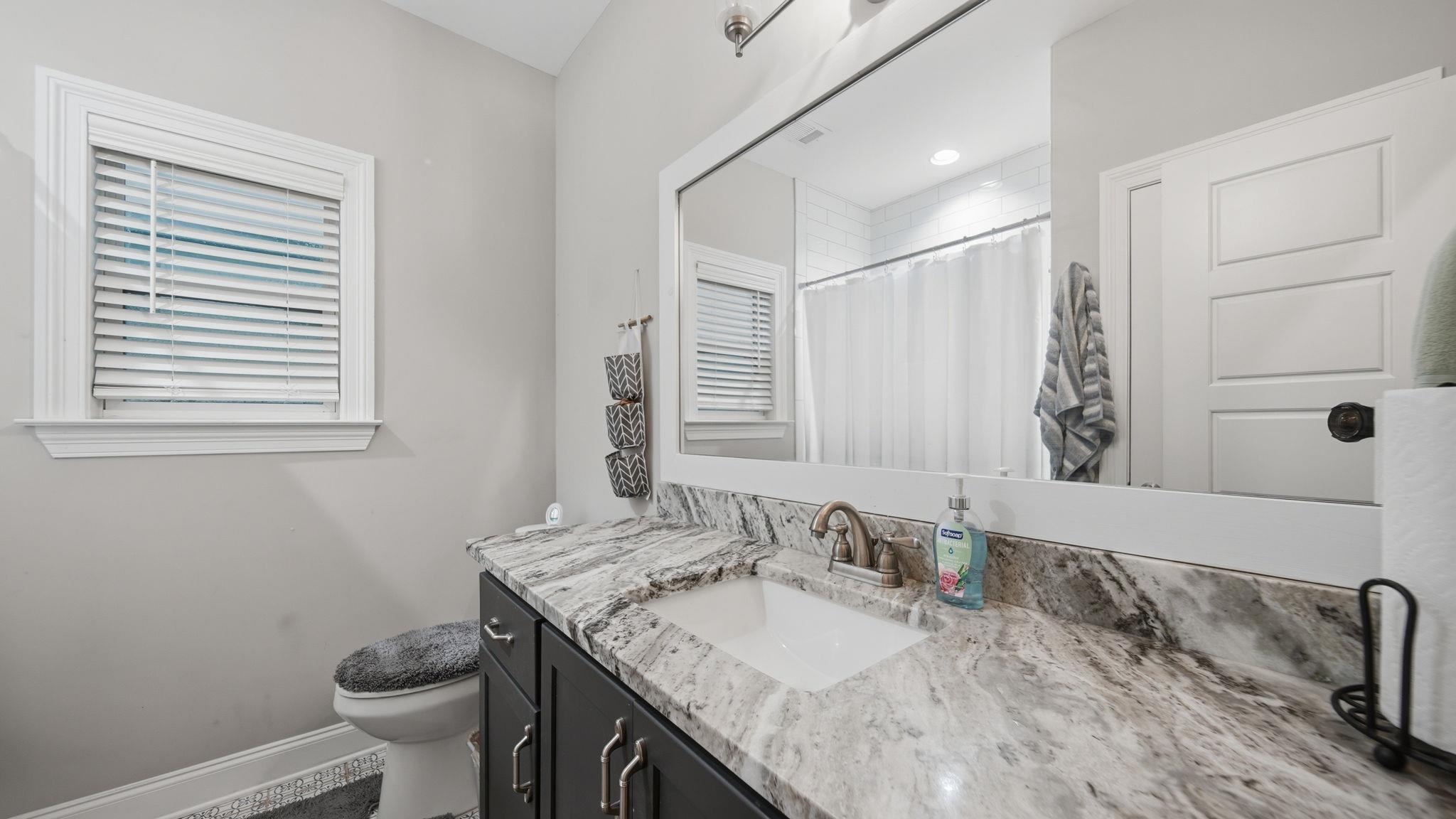 70 Trinity Cove Atoka, TN 38004 - Photo 15 of 25 Bathroom featuring a dark wood vanity with brushed nickel hardware, a white undermount sink, and a multi-toned stone countertop