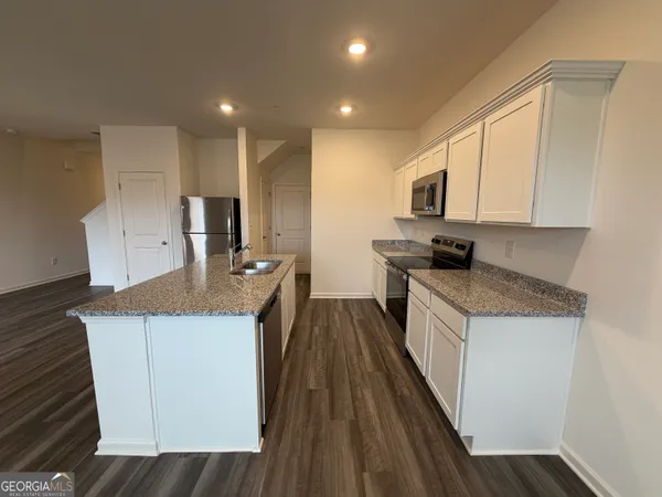 a kitchen with a sink a counter top space stainless steel appliances and cabinets