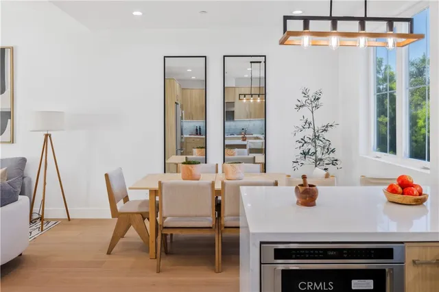 a kitchen with stainless steel appliances granite countertop a refrigerator a sink dishwasher a stove and white cabinets with wooden floor