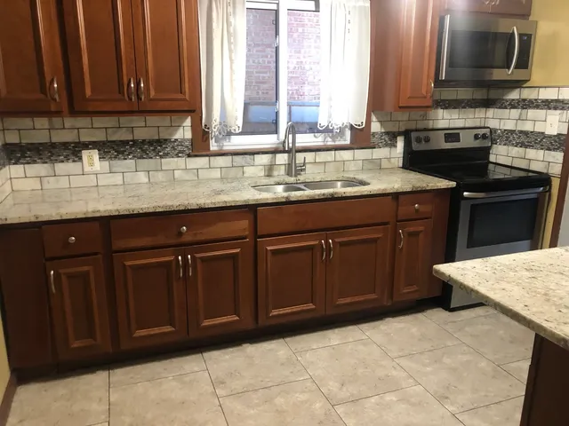 a kitchen with stainless steel appliances granite countertop a stove a sink and a microwave