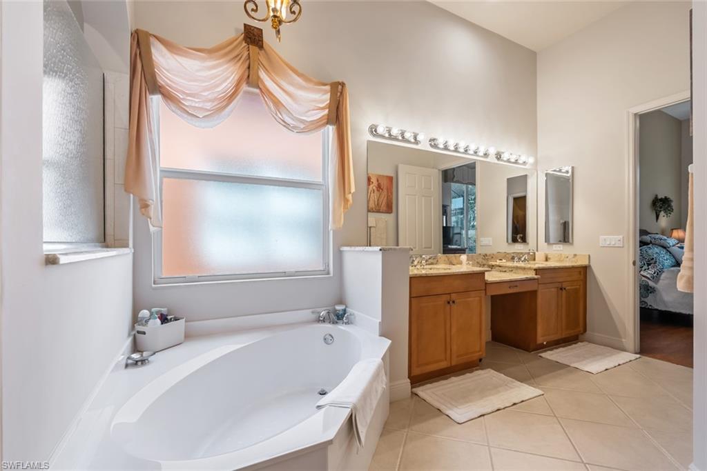 5757 Mango Circle Naples, FL 34110 - Photo 20 of 38 a bathroom with a tub a sink and a mirror