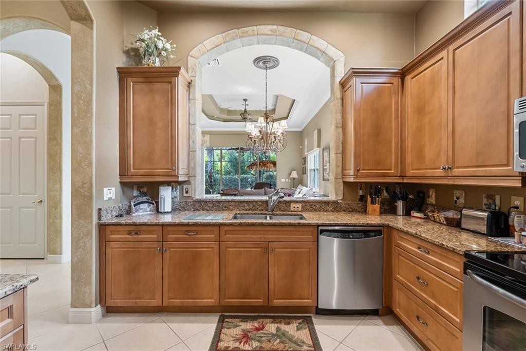 5757 Mango Circle Naples, FL 34110 - Photo 8 of 38 a kitchen with stainless steel appliances granite countertop a sink stove and cabinets