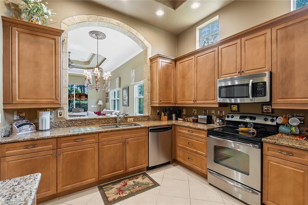 5757 Mango Circle Naples, FL 34110 - Photo 9 of 38 a kitchen with stainless steel appliances a stove sink and cabinets