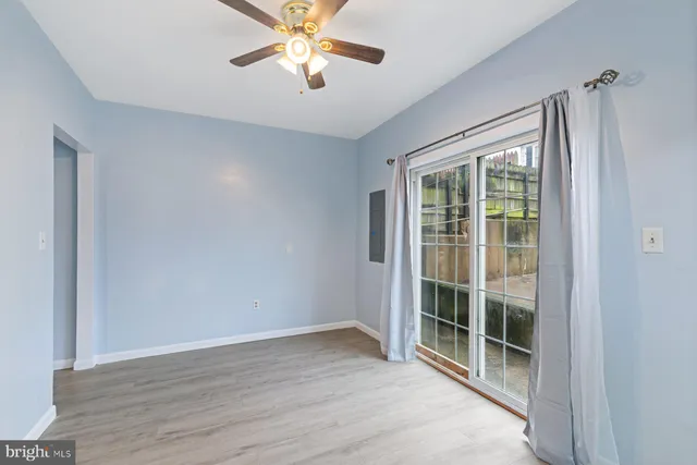 an empty room with wooden floor fan and windows